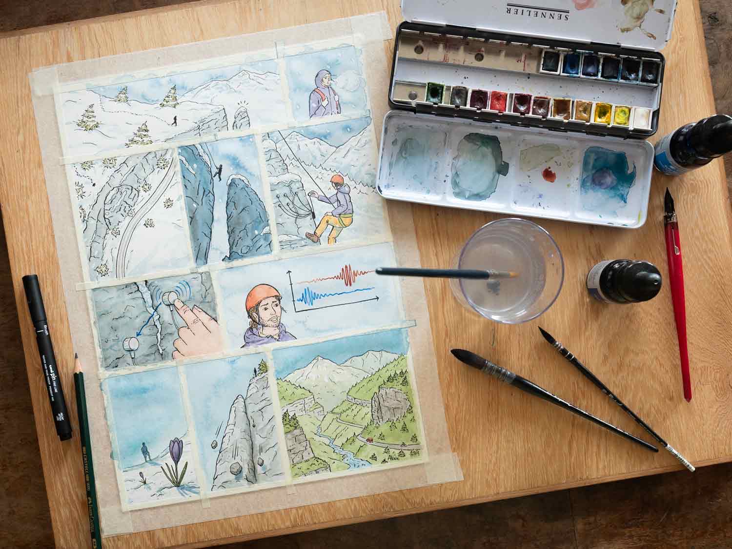 Planche de bande dessinée sur le bureau, avec la palette d’aquarelle et les pinceaux.